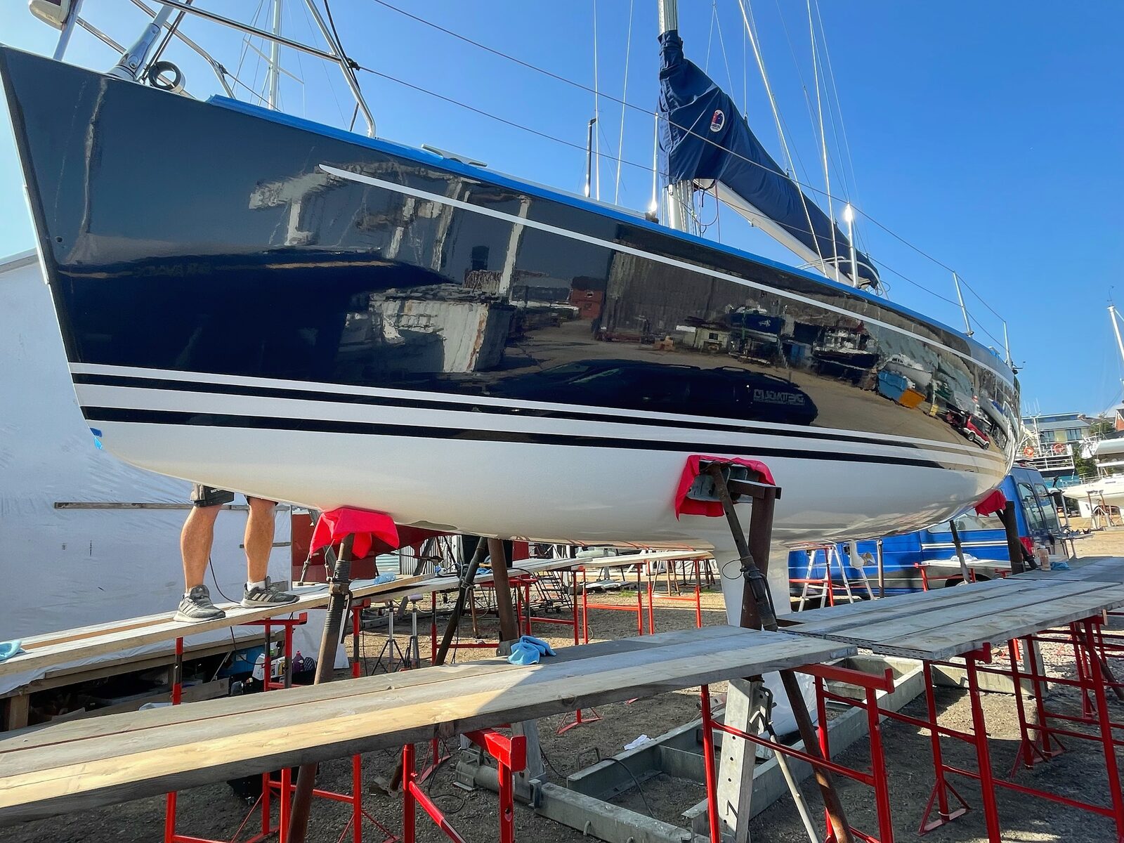 Arcona sailboat with dark blue hull on stand mid-prep