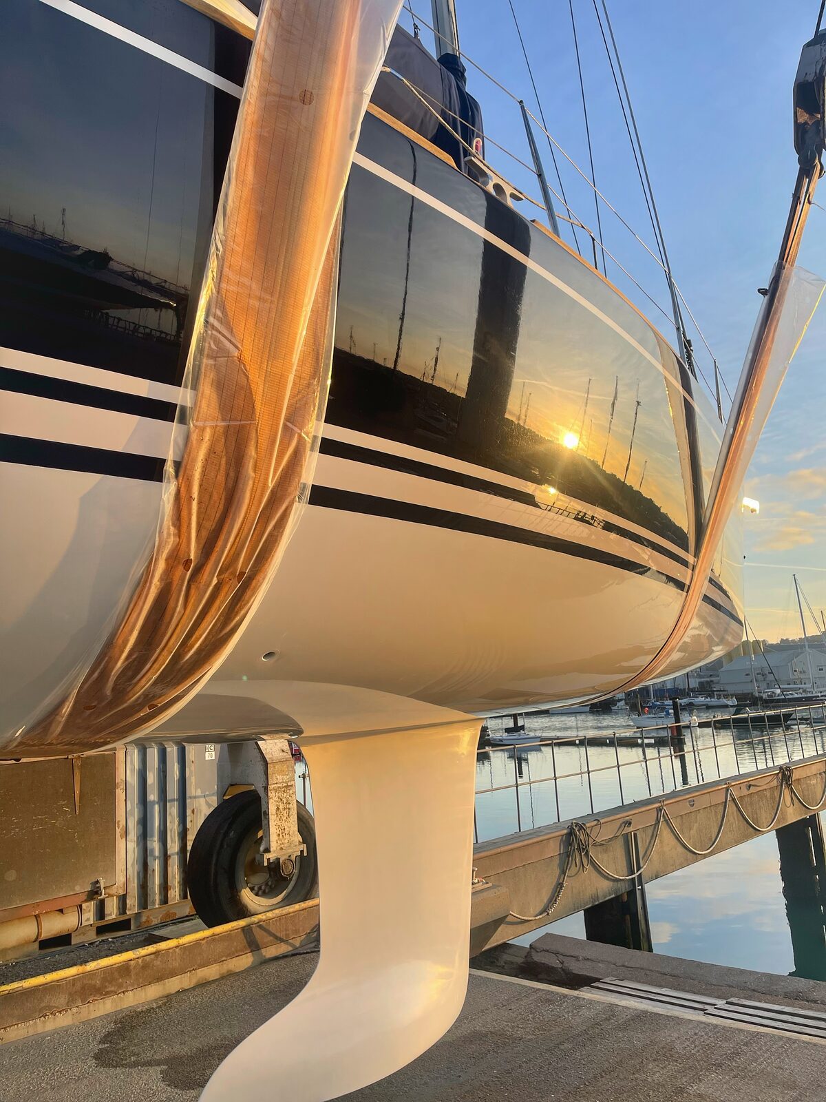 Coated sailboat hull picking up a golden sunset reflection