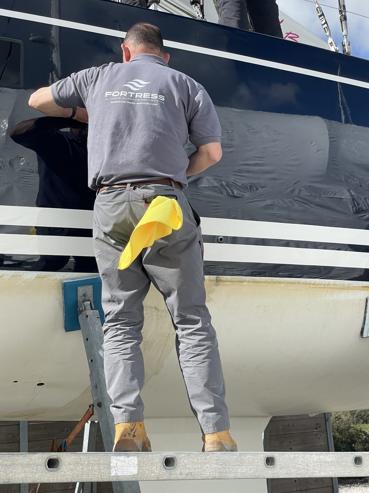 Fortress technician applying coating to a navy yacht hull